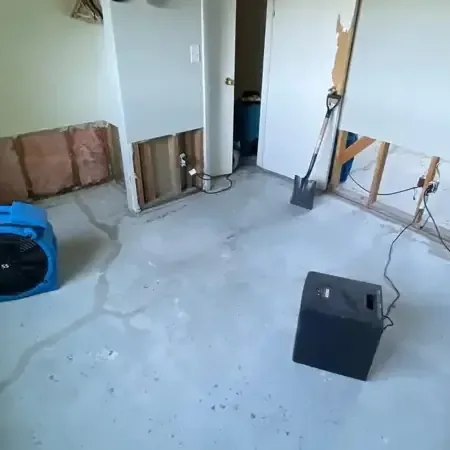 Air movers and a dehumidifier running in a room where the lower drywall was cut out and the floor is bare