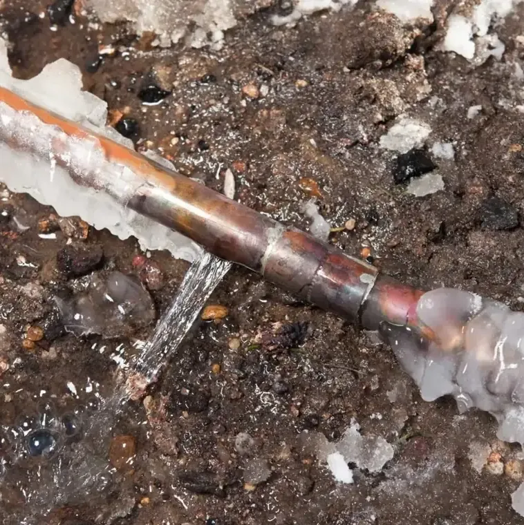 Split copper pipe leaking water through a coating of ice after a hard freeze