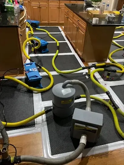 Hardwood drying mats and hoses laid across a kitchen floor during structural drying